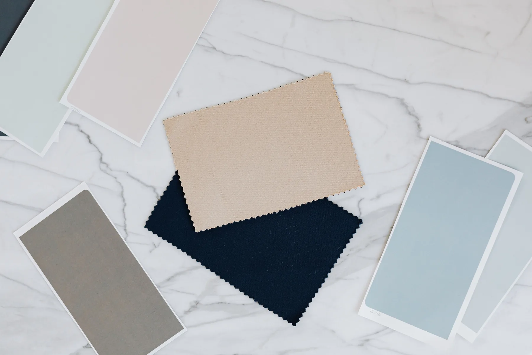Paint chips, stone and textile samples laid out on a marble table
